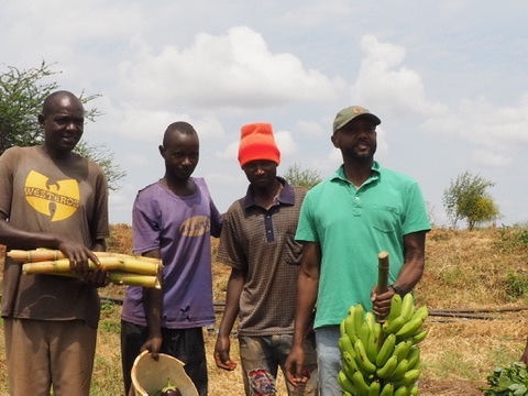 Farmers standing with sugarcane and bananas from their harvest