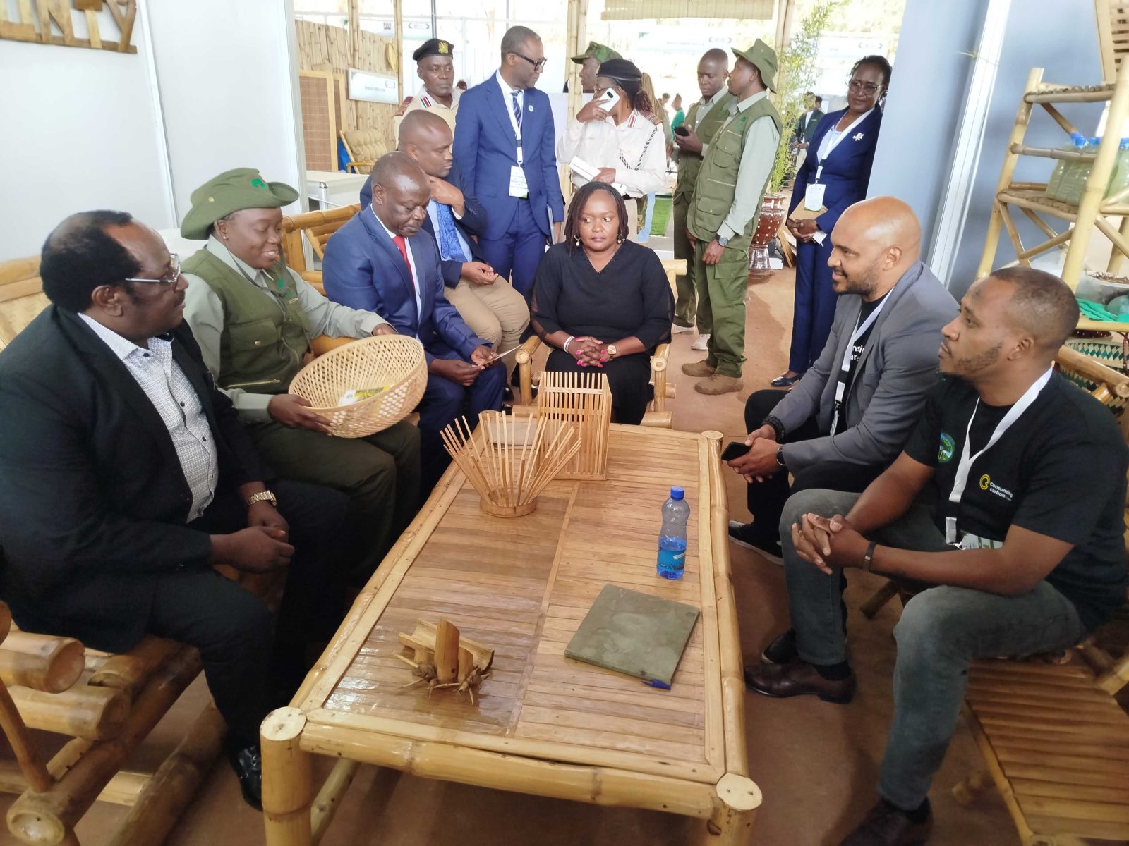 Cabinet Secretary Dr Deborah Barasa with the Consuming Carbon and EcoGreen Kenya team at our stand, seated on bamboo furniture made in Busia.