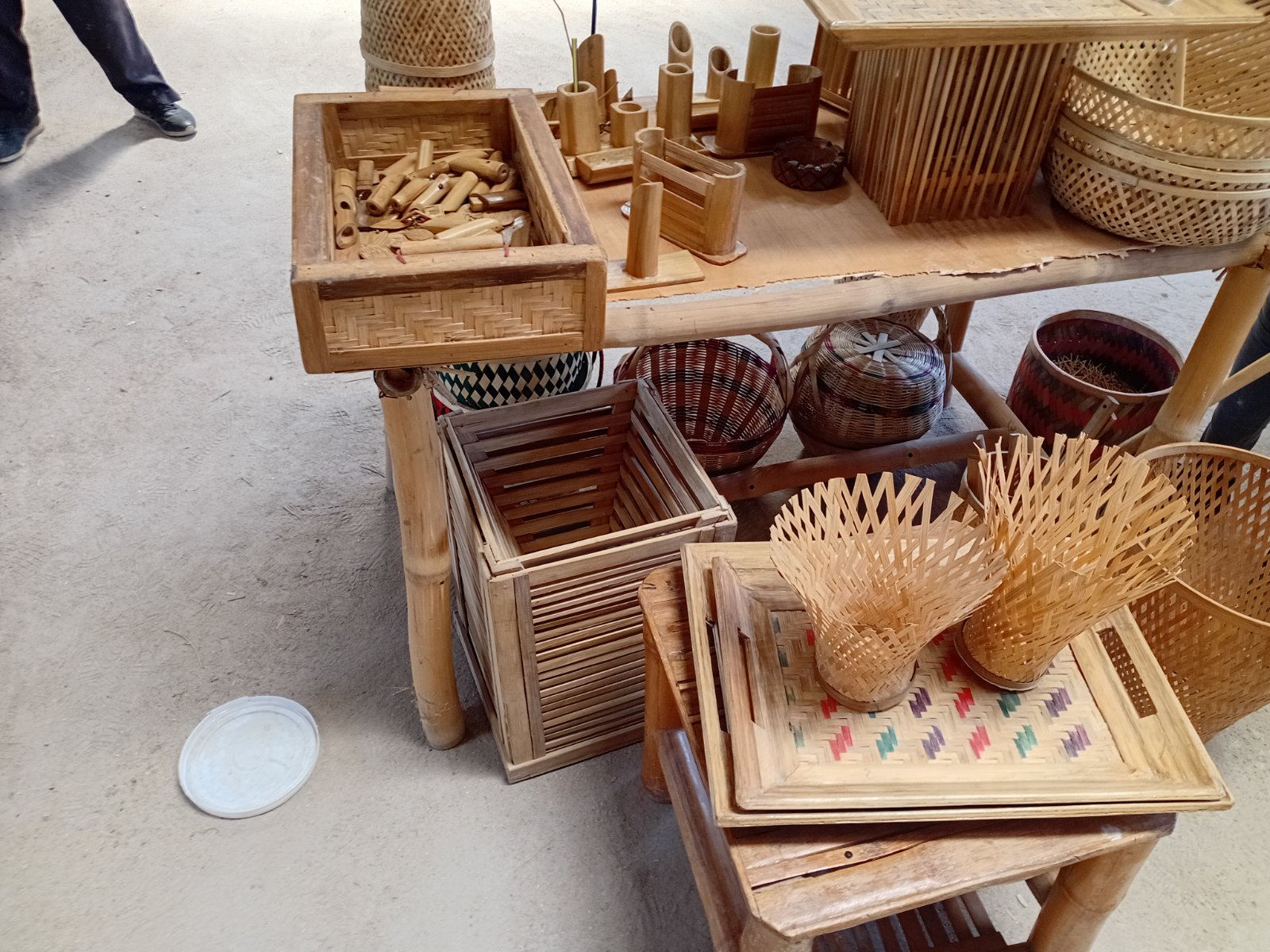 A display of finished bamboo goods at the EcoGreen workshop: woven baskets, trays, pen holders, and small carvings.