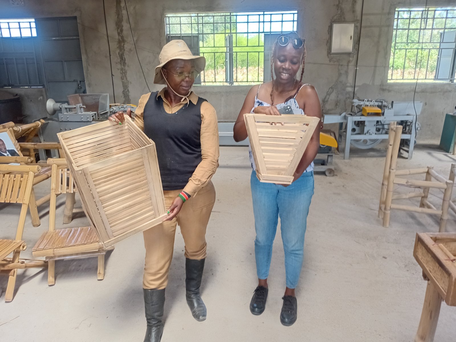 Two artisans at the EcoGreen cooperative workshop holding finished bamboo lampshade frames.